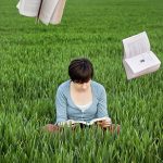 woman field reading book, books flying in the air